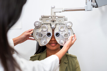 Optician examining patient eyesight with phoropter during eye exam