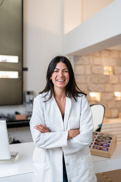 Portrait of smiling female optician standing with arms crossed