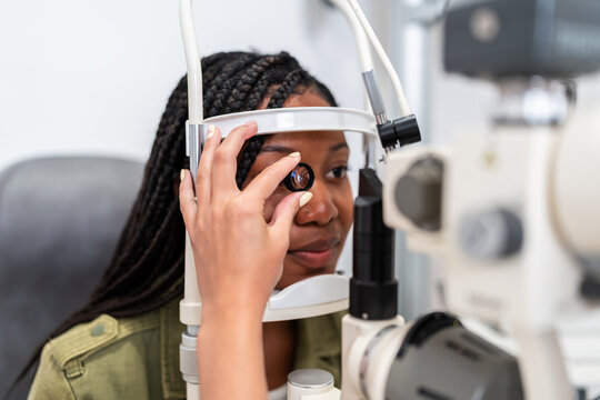Optician examining patient eyesight with phoropter during eye exam