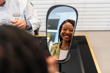 Woman trying new eyeglasses smiling looking in the mirror