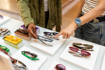 Women choosing eyeglasses in optical store, shopping for eyewear