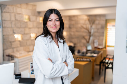Optician smiling with crossed arms standing in optical store