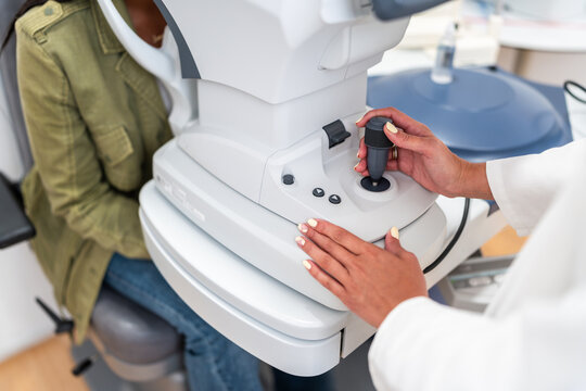 Optician using joystick of autorefractor during eye examination