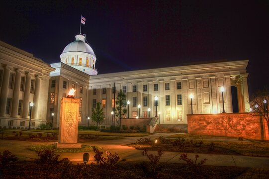 Dramatic night view of the historic Alabama State Capitol building in Montgomery, AL, beautifully illuminated against the dark evening sky.