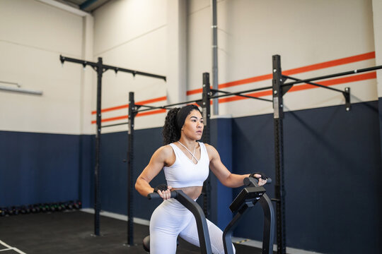 Young Latina training on elliptical machine at the gym