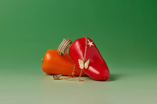 Jewelry and mini sweet peppers on a gradient green background