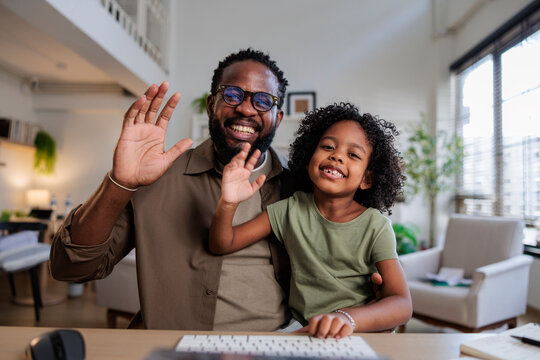 Father and daughter wave hello on video call