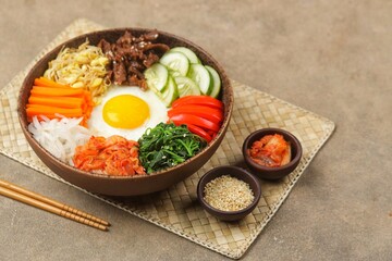 Bibimbap is a Korean dish in the form of a bowl of white rice topped with side dishes of vegetables, beef, eggs and spicy gochujang sauce.