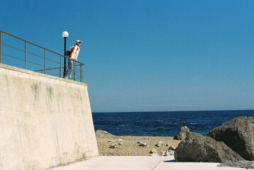 A middle-aged woman admires the sea view from the embankment.