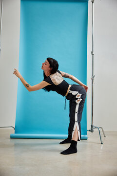 Woman posing dynamically in studio with bright blue backdrop