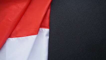 Crumpled red and white Indonesian flag with copy space area isolated on black background