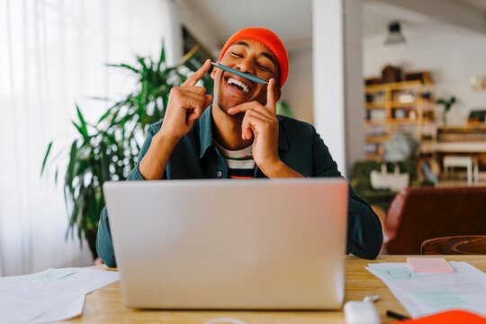 Man balancing pen on upper lip at desk