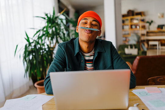 Man balancing pen on upper lip at desk