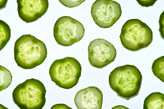 Fresh cucumber slices making pattern on a white background.