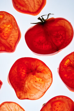Fresh tomato slices making pattern on a white background.