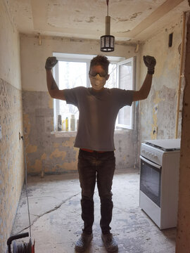 Renovation worker flexing arms in dusty kitchen