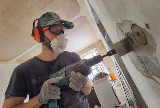 Man drilling wall during apartment renovation