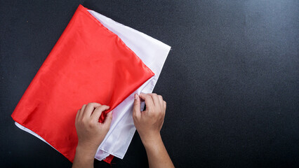 Top view of hands holding red and white Indonesia flag color isolated on black background