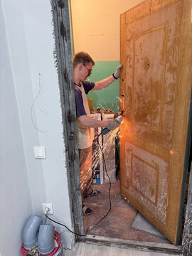 Man cutting metal door lock with angle grinder