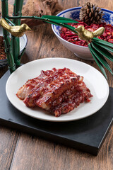 Honey-glazed barbecued pork in a rice-colored porcelain plate is placed on a camphorwood cutting board