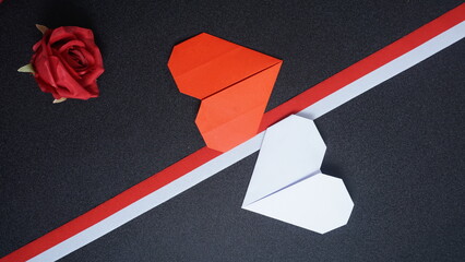 Independence Day Indonesia banner mockup with a rose, Indonesia flag color ribbons and heart shaped origami isolated on black background