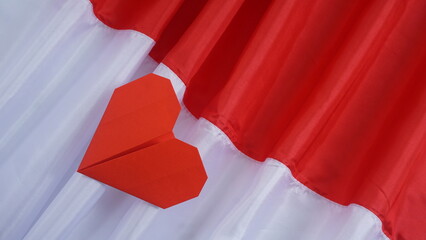 Red heart shaped origami on red and white Indonesia flag fabric isolated