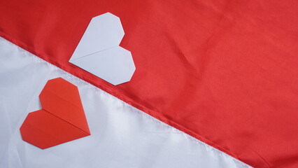 Red and white heart shaped origami on red and white Indonesia flag fabric isolated