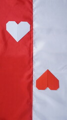 Red and white heart shaped origami on red and white Indonesia flag fabric isolated