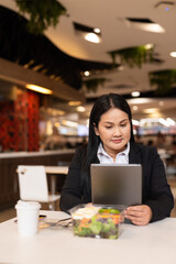 Portrait of a woman in cafe using digital tablet computer and having salad