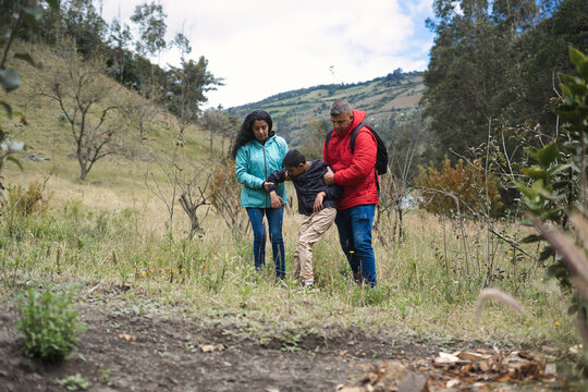 Parents helping injured son while hiking in the countryside