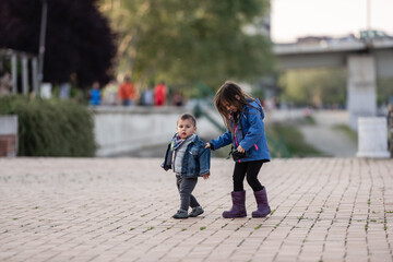 Older sister helping younger brother while walking in park
