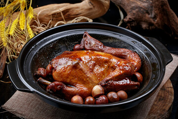 A black casserole of raw chicken is placed on a curtain mat