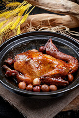 A black casserole of raw chicken is placed on a curtain mat
