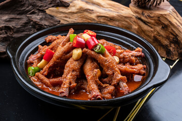 Chicken feet in garlic casserole placed on black background