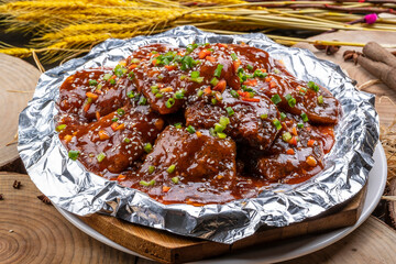 Braised boneless hairtail in a foil tray on a camphorwood chopping board