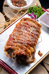 Mongolian roasted lamb back in a red lacquered wooden tray on a camphorwood chopping board