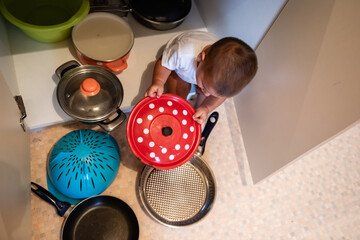Baby playing with pots and pans in kitchen cabinet