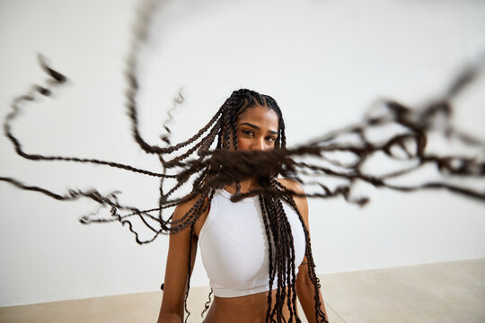 Person with long braids showcases a dynamic hairstyle in a studi