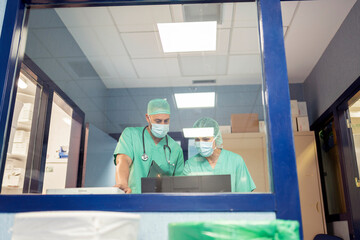 Two surgeons wearing masks working with computer in operating room