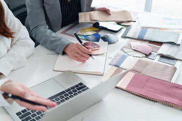Asian Women Interior Designers Brainstorming Design Ideas with Fabric Samples and Laptop for Creative Projects in Studio