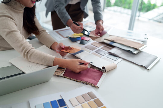Asian woman interior designer team working with fabric sample, color palette for home renovation project. Architect choosing material for building design. Collaboration on modern decor ideas