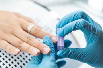 Professional Manicure Process with Gloved Hands and Buffing Block