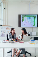 Asian Interior Designers Collaborate on Project Discussing Color Palettes and House Plans at Office Workplace for Creative Designs