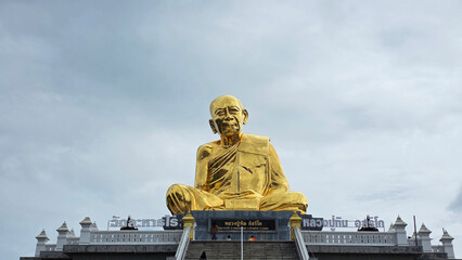 Majestic golden statue of revered monk Luang Pu Tim at Wat Lahan Rai in Rayong, Thailand, captured...