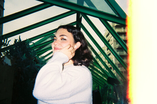 Young woman smiling under green roof structure
