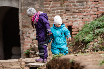 Two children exploring abandoned building ruins holding hands