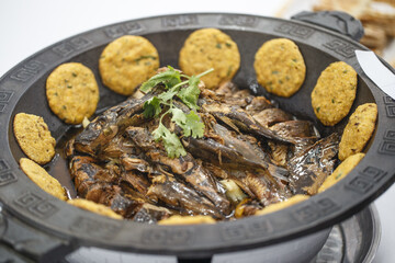 Traditional famous dish of stewed fish with pancakes in exquisite iron pot