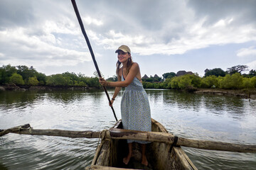 A tourist girl is rowing an old boat on the Congo River in Africa. view of woman paddling wooden...