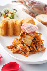 Stir-fried pork belly with spicy cabbage and fried steamed bread slices served on a plate