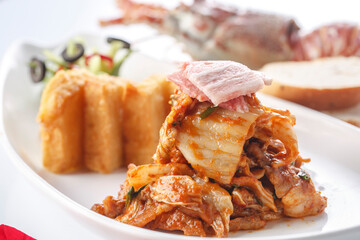Stir-fried pork belly with spicy cabbage and fried steamed bread slices served on a plate